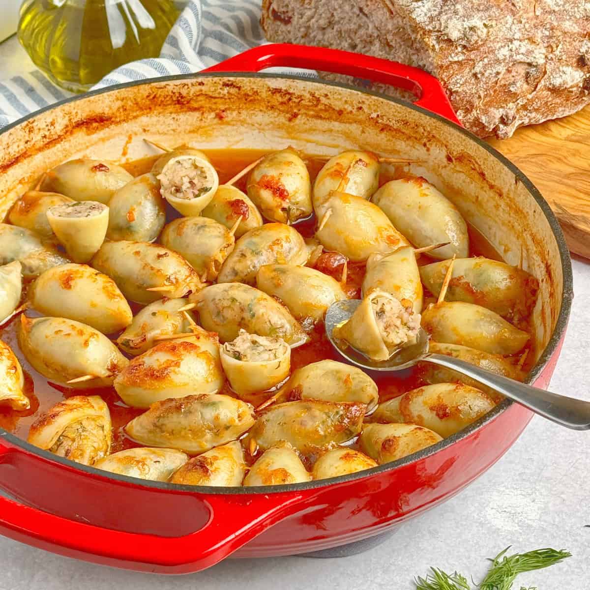 Stuffed calamari in red pan next to loaf of bread.