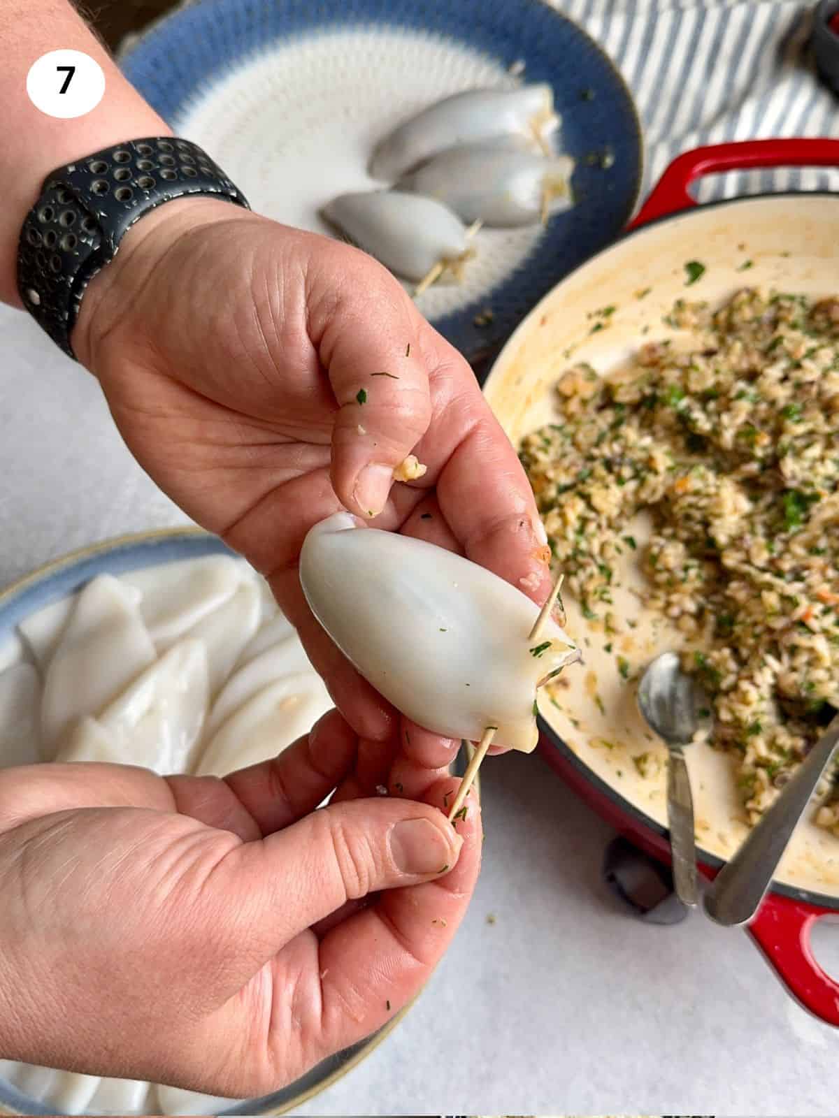 Placing a toothpick at the tip of the stuffed calamari tube.