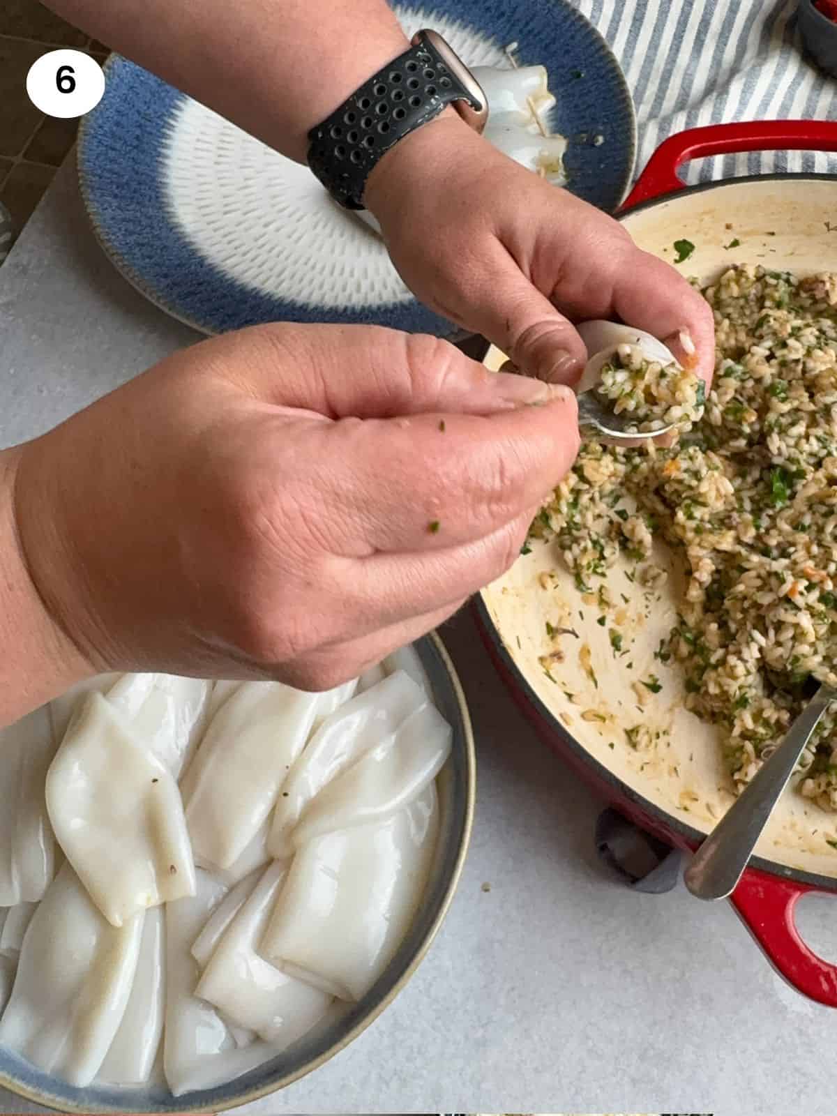 Stuffing a calamari tube using a teaspoon.
