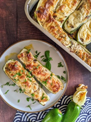 Stuffed zucchini with ground beef and bechamel sauce placed on a plate with some basil on top.