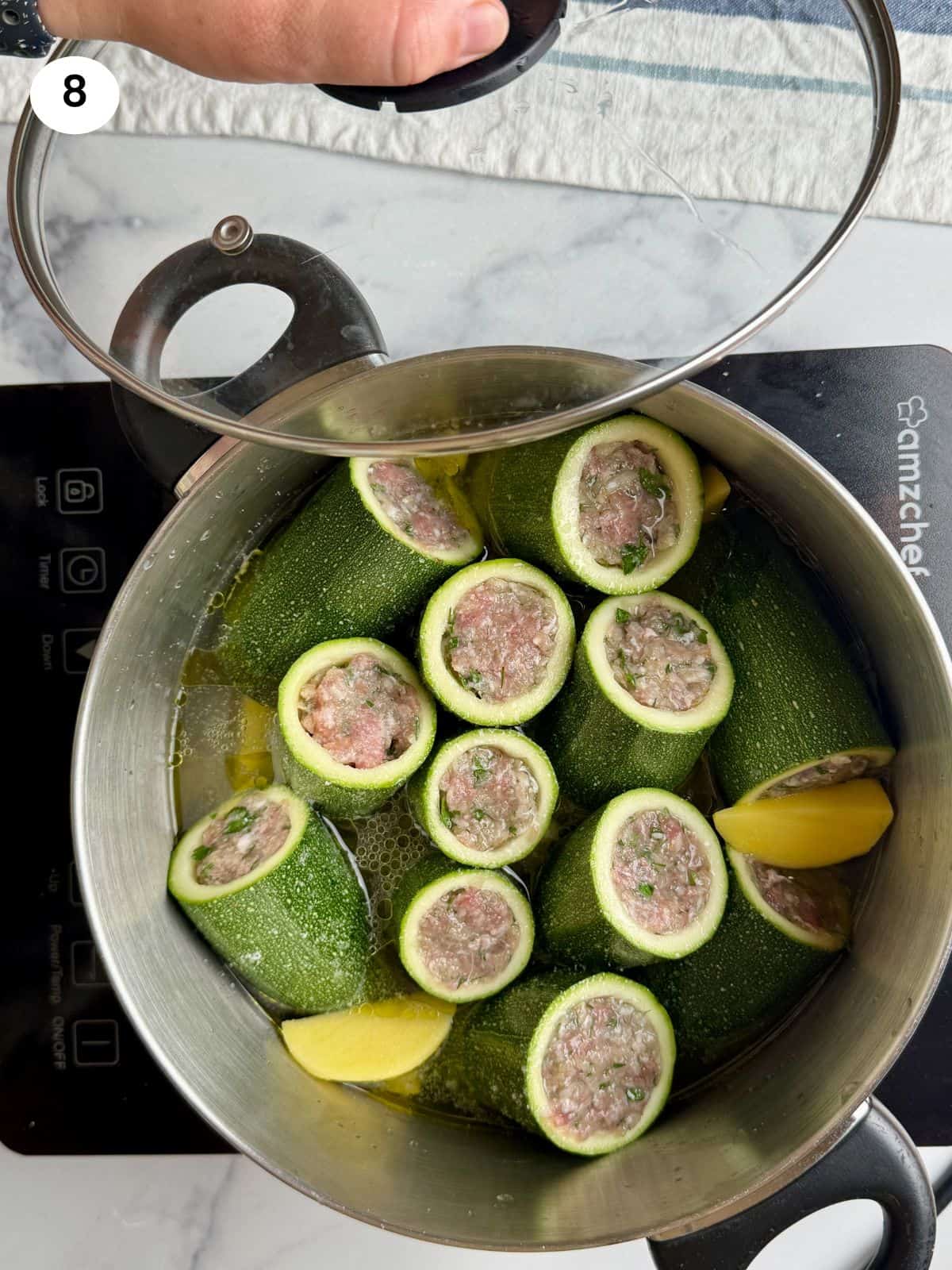 Stuffed zucchini in the pot with water and ready to cook.