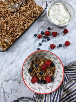 Coconut granola in a bowl served with raspberries and yogurt