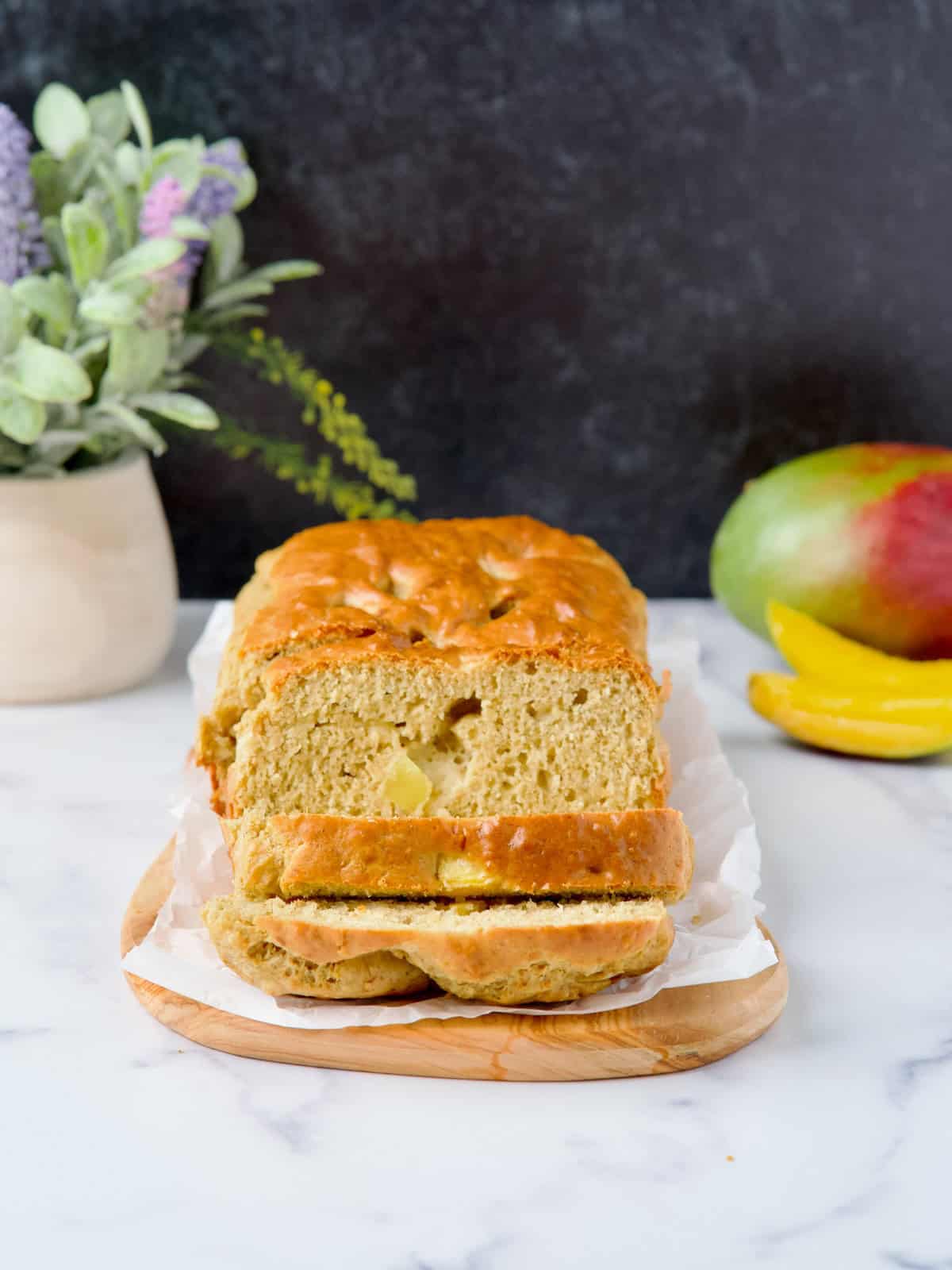 Sugar-free Mango & Banana bread served on wooden board next to a mango and a banana