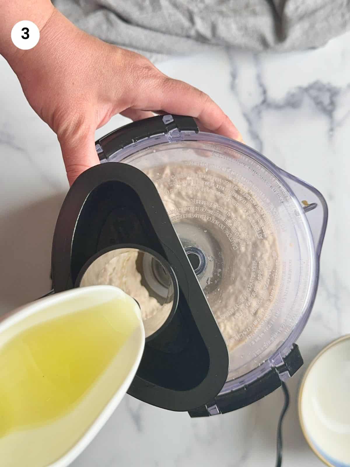 Pouring the oil in the food processor.