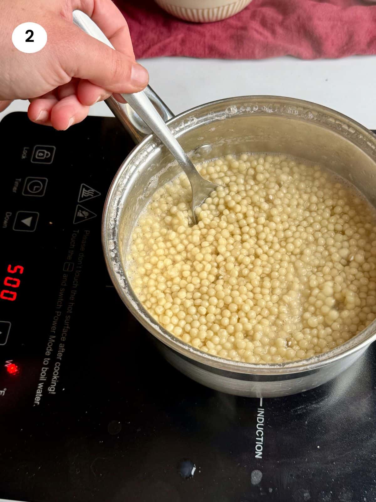 Cooking the pearl couscous in a pot.