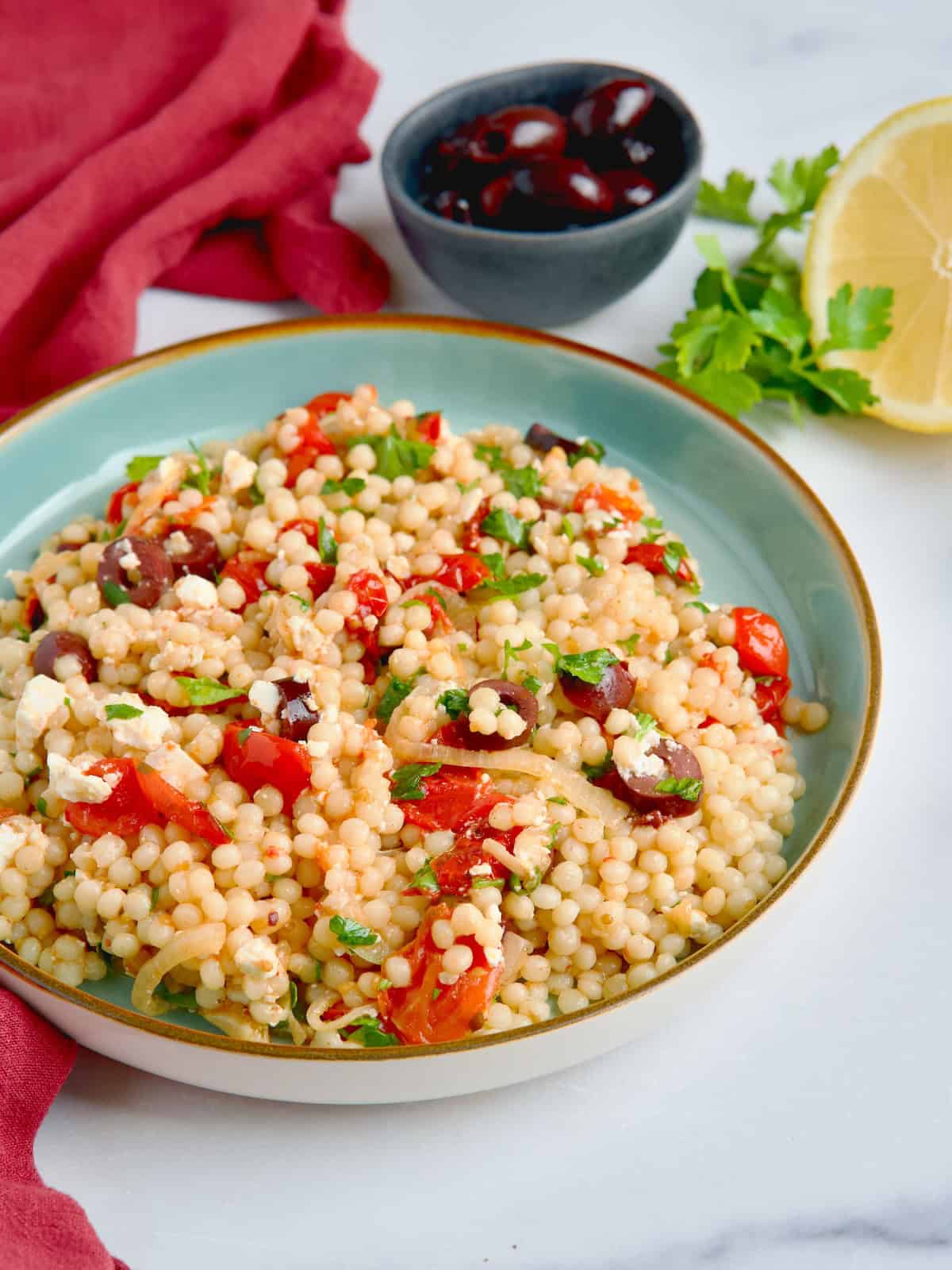 Pearl couscous salad served in a blue plate.