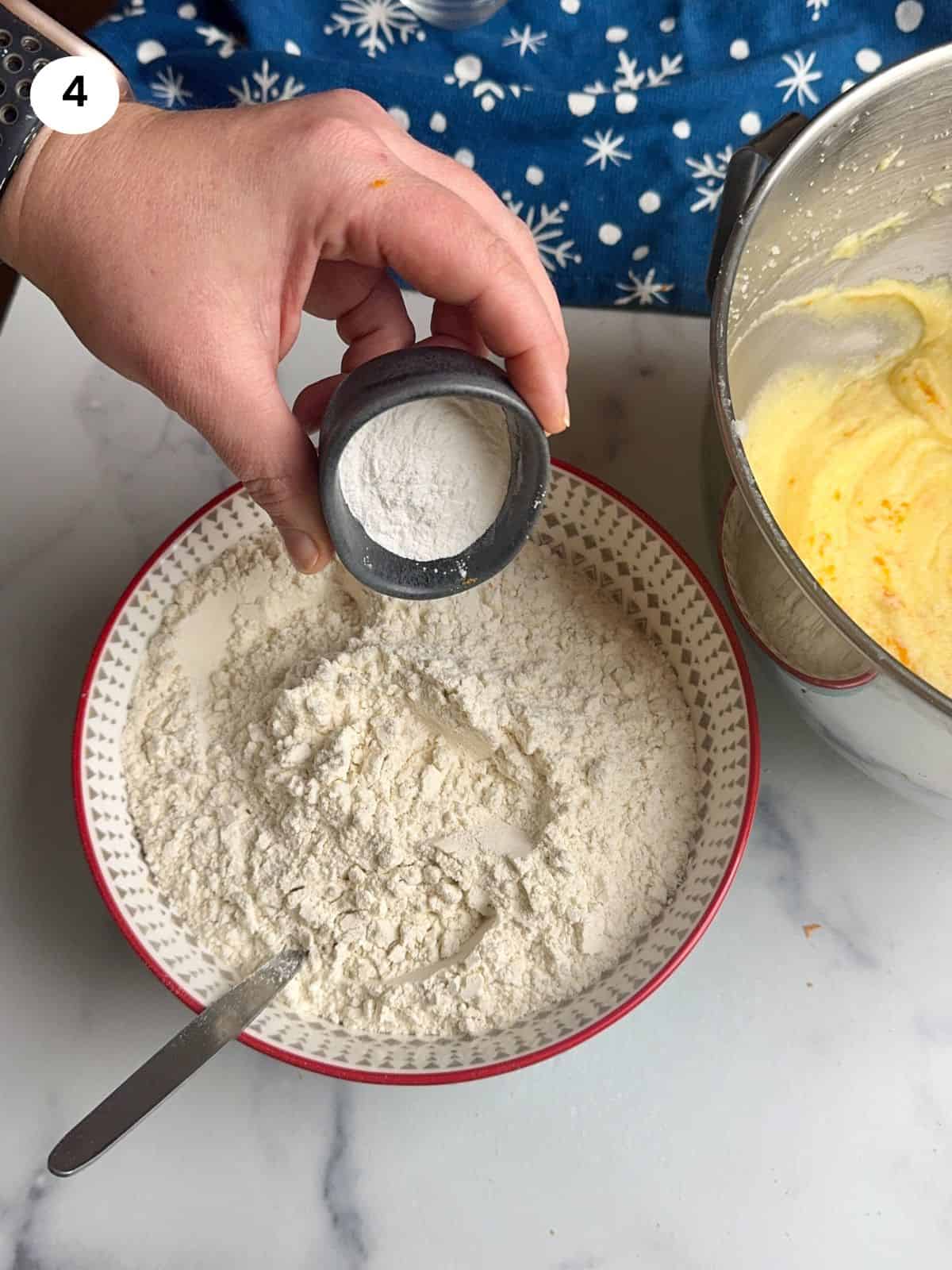 Adding baking powder to the flour bowl.