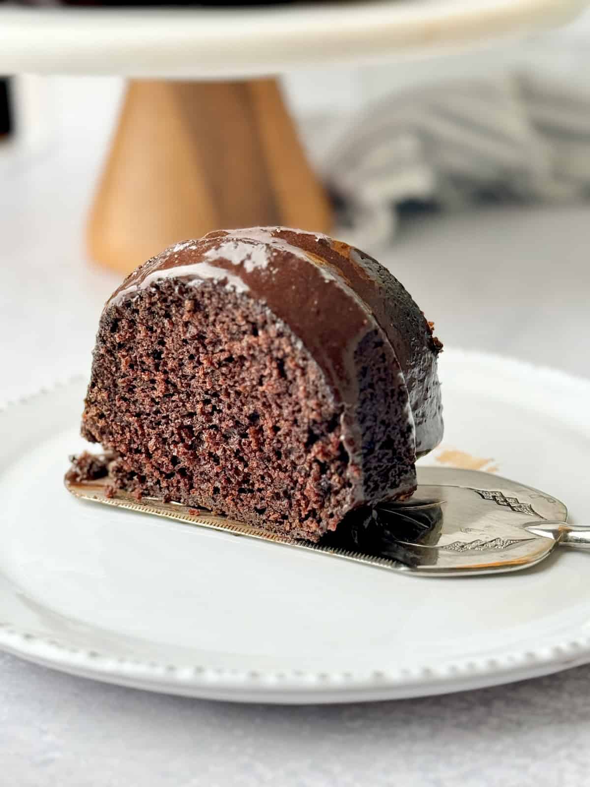 Slice of chocolate cake on white plate.