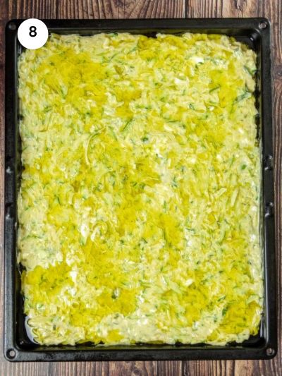 Zucchini pie in the tray with olive oil on top.