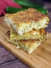 Three slices of crustless zucchini pie stack on top of each other on a wooden board.